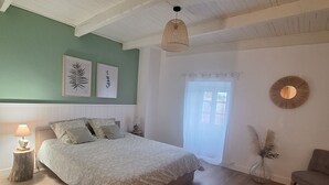 A bedroom with a bed, a round rug, a side table with a lamp, a vase with dried flowers, and a wall-mounted mirror. - L'Annexe de la Bastide - Stone house with swimming pool (Ribes)
