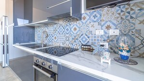 A modern kitchen with a built-in stove, a microwave, and a sink. - Apartment 'I Due Mori Marzamemi' with Sea View, Wi-Fi and Air Conditioning (Marzamemi)