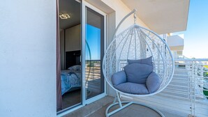 A balcony with a hanging chair, a sliding glass door leading to a bedroom, and a view of the sea. - Apartment 'I Due Mori Marzamemi' with Sea View, Wi-Fi and Air Conditioning (Marzamemi)