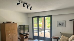 Una sala de estar moderna con una televisión de pantalla plana sobre un mueble de madera, un sofá, una mesa de centro y un aparador.