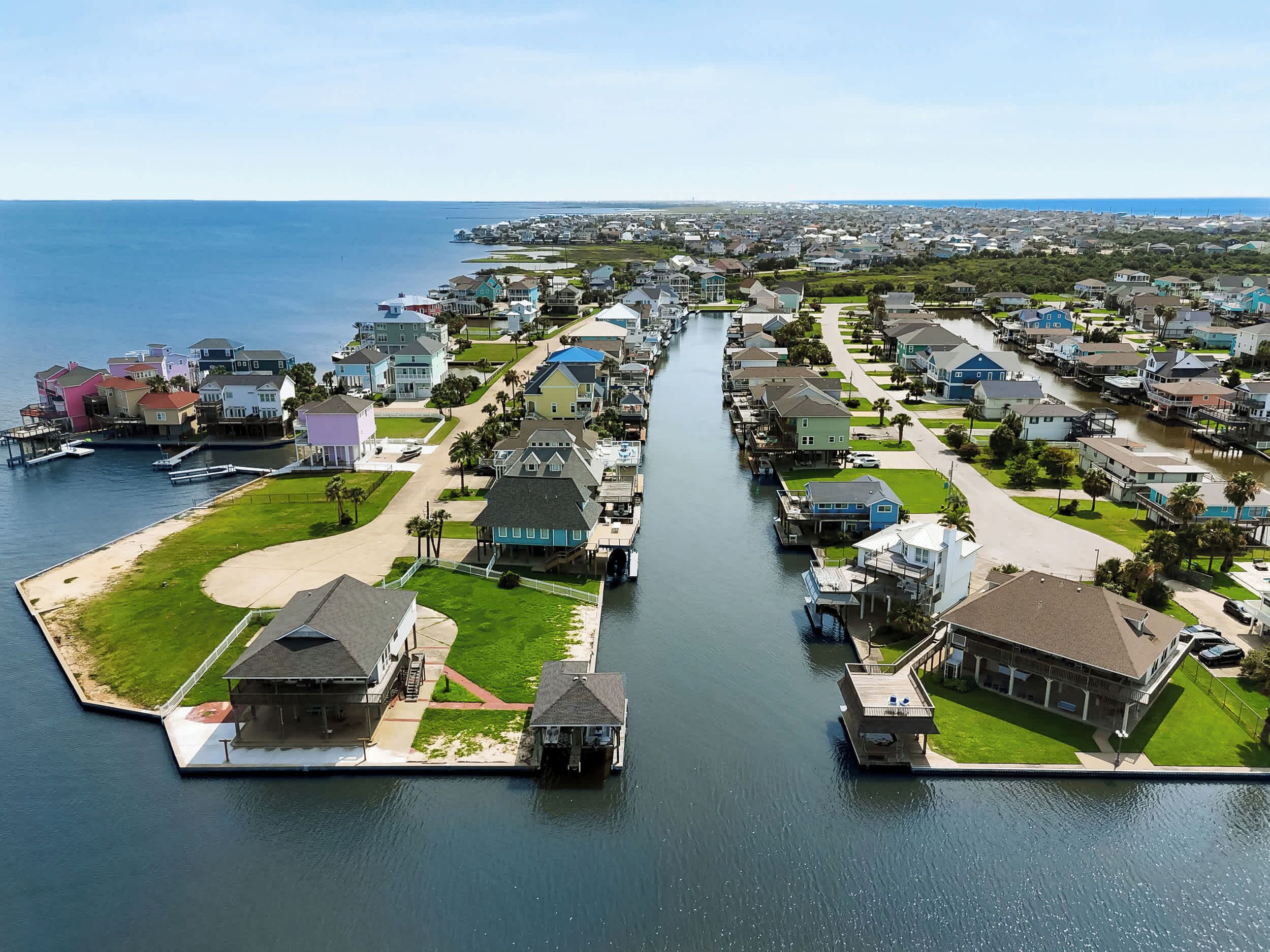 A residential area with houses along a waterway, docks, and a clear view of the water.