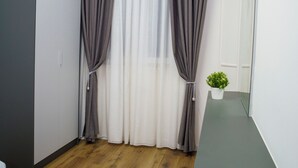 Una habitación moderna con piso de madera, un armario gris y una pequeña planta en maceta sobre una estantería.