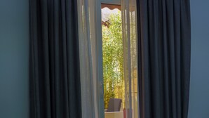 Una habitación con vistas a un balcón, una mesa de centro de vidrio y una alfombra estampada.