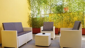 Un área de estar con muebles de mimbre y una pequeña mesa, rodeada de plantas de bambú.