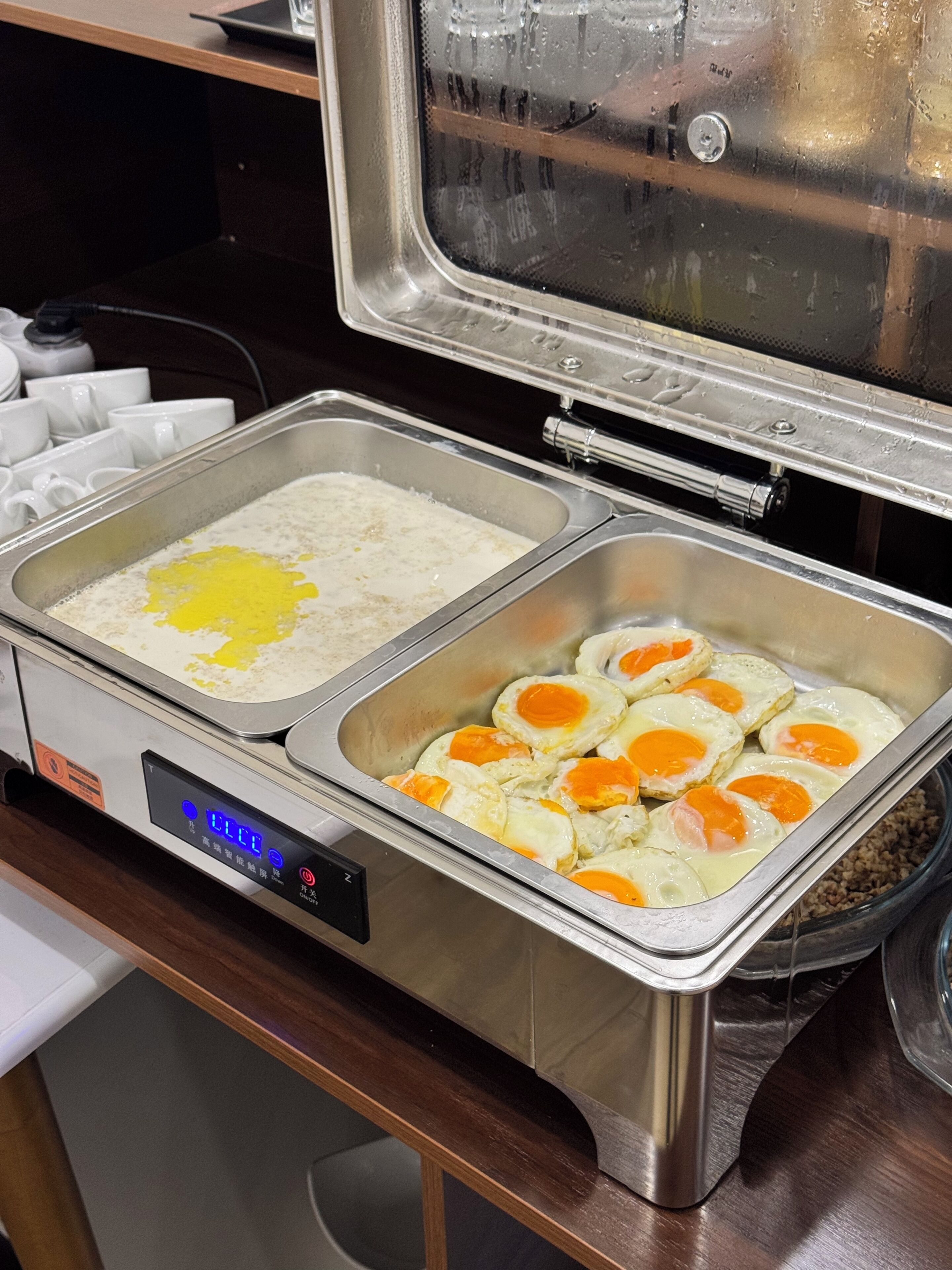 A buffet setup with a digital control panel, two food service stations, and a stainless steel container.