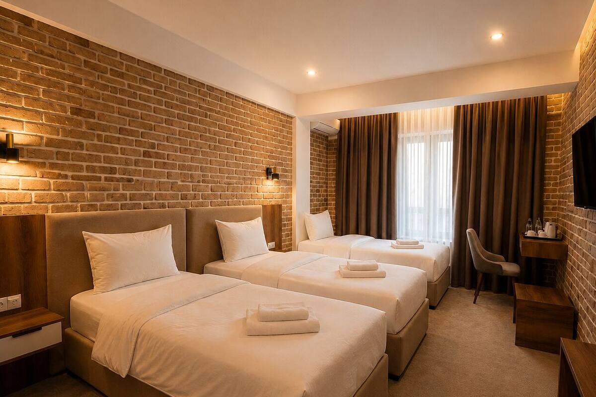 A hotel room with two beds, a desk, a chair, and a TV.