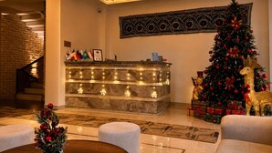 Un vestíbulo con mostrador de recepción, un árbol de Navidad y una escalera.