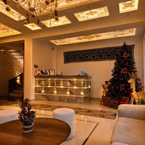Un vestíbulo con mostrador de recepción, un árbol de Navidad y una escalera.