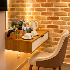 Una habitación moderna con pared de ladrillo, un escritorio de madera con cafetera, tazas y un teclado.