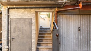 Une série de marches en pierre menant à une entrée fermée par un portail, avec une porte en métal et un mur en béton.
