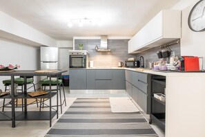 A modern kitchen with grey cabinets, a stainless steel refrigerator, a microwave, and a red toaster.