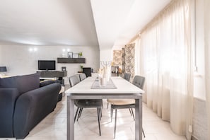 A modern living room with a sofa, dining table, and TV.