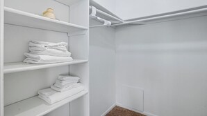 A white closet with shelves holding folded towels and a white pipe running along the wall. - Apt. In college Station TX Mins to major hospitals and A&M U (College Station)