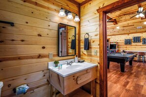 A wooden interior with a sink, mirror, and a pool table in the background. - 6-Bedroom Cabin with Indoor Pool & Hot Tub, Sleeps 24, Near Gatlinburg (Sevierville)