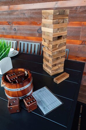 Een houten Jenga-toren, een houten emmer met dobbelstenen en een scoreblad op een tafel.