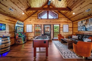 Een gezellige kamer met een tafelvoetbaltafel, een bar met spelautomaten en een comfortabele zithoek met een bank en stoelen.