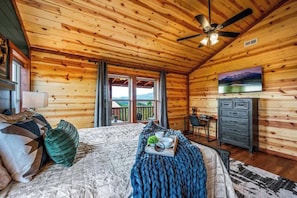 A wooden cabin bedroom with a bed, a desk, a chair, and a television. - 6-Bedroom Cabin with Indoor Pool & Hot Tub, Sleeps 24, Near Gatlinburg (Sevierville)