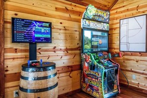 A wooden interior with a mounted video game console and a monitor displaying a game menu. - 6-Bedroom Cabin with Indoor Pool & Hot Tub, Sleeps 24, Near Gatlinburg (Sevierville)