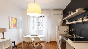 A modern kitchen with white cabinetry, a black backsplash, and a hanging light fixture. - Two-room Apartment Peace Arch - Mirable PM (Milano)