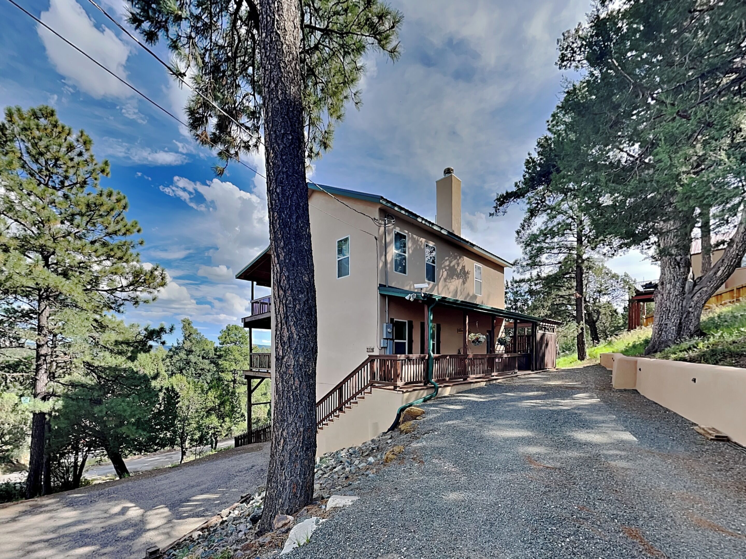 Une maison à deux étages avec un porche, entourée d’arbres.