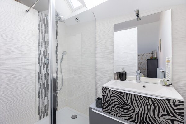 A modern bathroom with a shower, a zebra-patterned vanity, a large mirror, and a skylight.