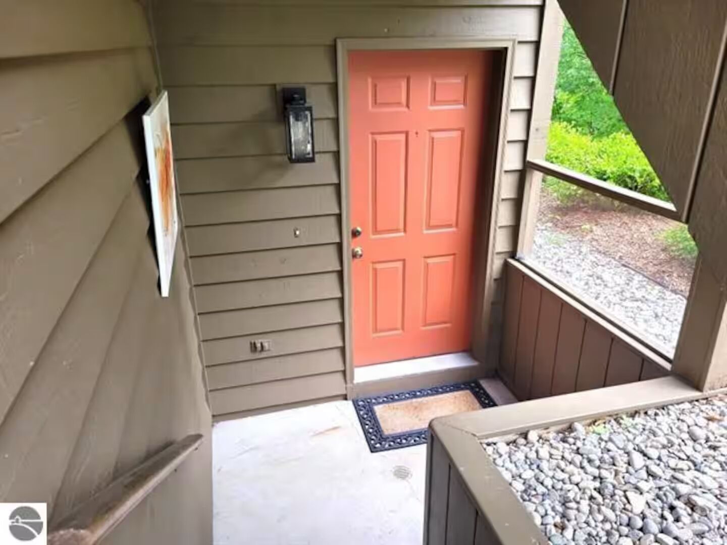 Eine Holzwand mit roter Tür, Briefkasten und kleinem Fenster.