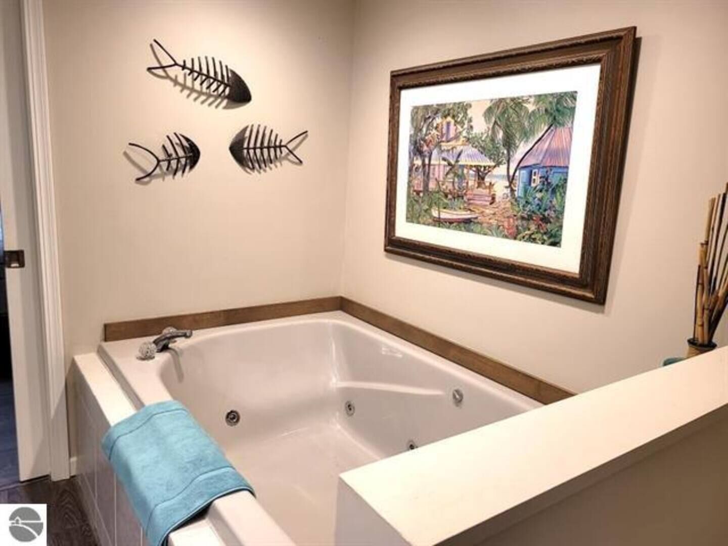 A bathroom with a large bathtub, a framed painting on the wall, and decorative fish skeletons.