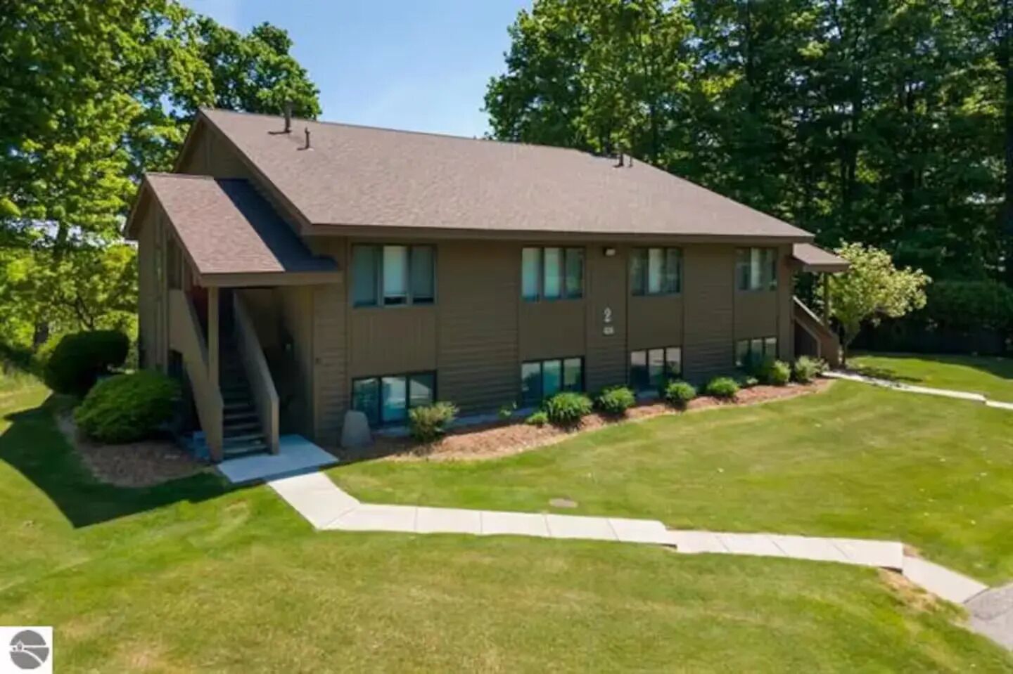A two-story building with a sloped roof, a covered front porch, and a well-maintained lawn.