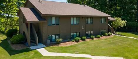 A two-story building with a sloped roof, a covered front porch, and a well-maintained lawn.
