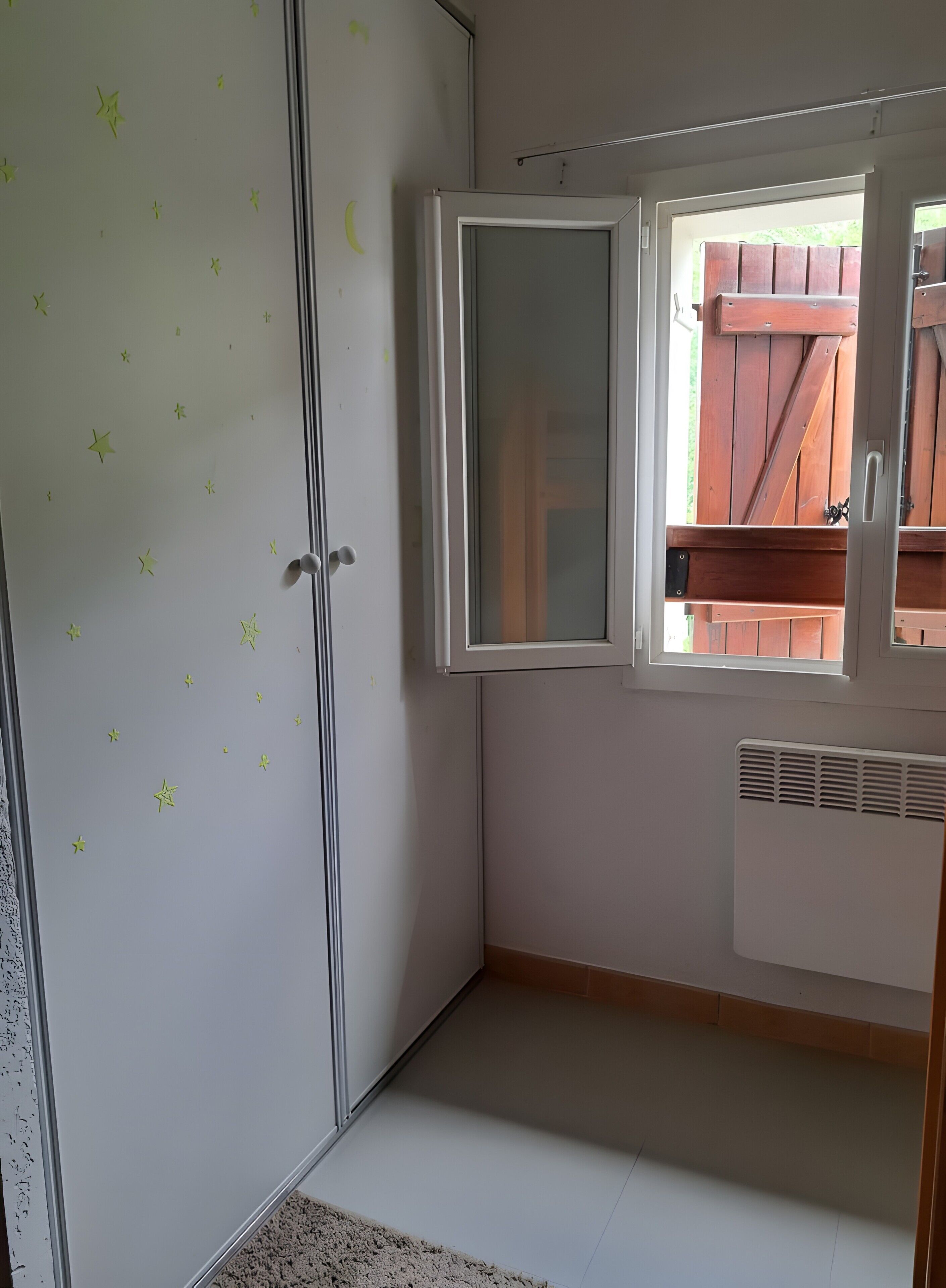 Una habitación con armario, ventana y radiador.