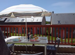 An outdoor dining area with a table, chairs, an umbrella, and a railing. - Holiday Home 'Duplex Near Lake La Raviège' with Private Terrace and Private Garden (La Salvetat sur Agout)