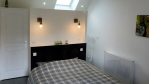 A bedroom with a skylight, two wall-mounted lights, a radiator, and a bed with a plaid bedspread. - Bed and Breakfast 'Vert Ailleurs' with Shared Terrace, Shared Garden and Wi-Fi (Tavant)