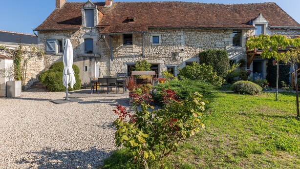 A stone building with a tiled roof, a gravel driveway, and a patio area with outdoor furniture. - Bed and Breakfast 'Vert Ailleurs' with Shared Terrace, Shared Garden and Wi-Fi (Tavant)