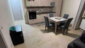 Eine kompakte Küche mit Essbereich, inklusive Tisch und Stühlen, sowie ein kleiner Fernseher auf der Arbeitsfläche.