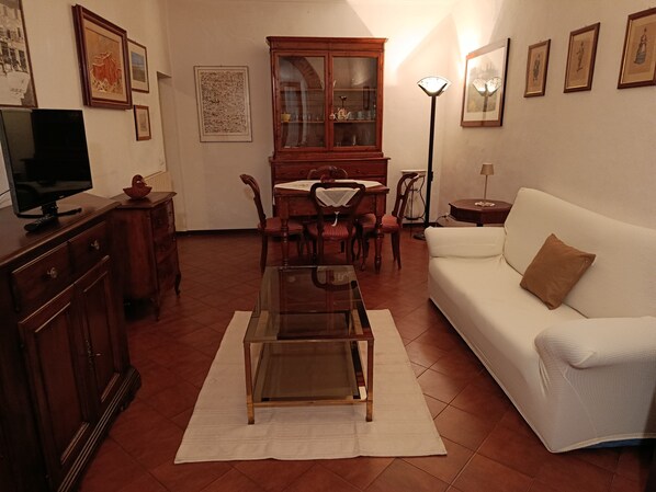 Un salon avec un canapé blanc, une table basse en verre, un meuble en bois et une table à manger avec des chaises.