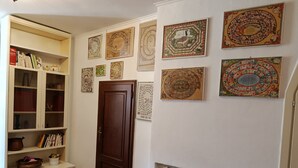Un couloir avec une porte en bois, un radiateur et une bibliothèque remplie de livres et d’objets décoratifs.