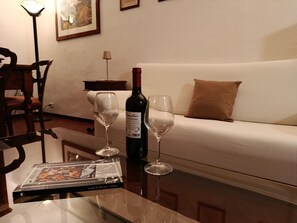 Un salon avec un canapé, deux verres à vin, une bouteille de vin et un magazine sur une table basse.