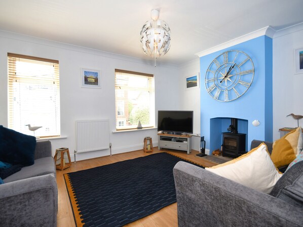 Ein Wohnzimmer mit einer großen blauen Wanduhr, einem Kamin und einem Fernseher.