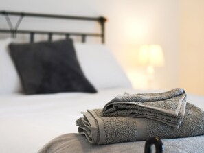 Ein ordentlich bezogenes Bett mit einer grauen Decke und einem Kissen.
