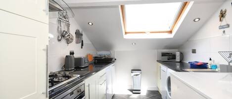 A compact kitchen with a skylight, modern appliances, and a small laundry area.