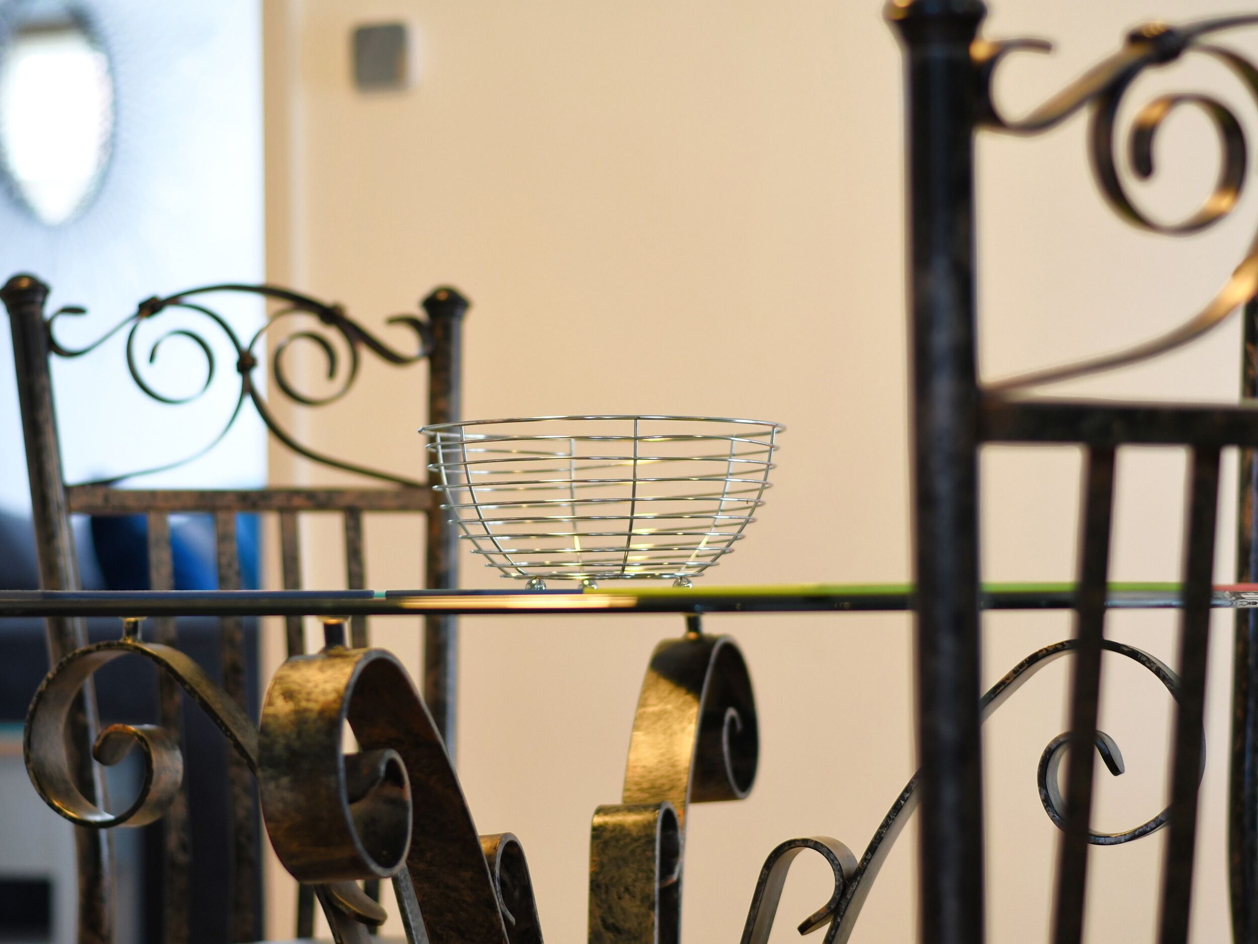 A metal chair with a wire basket on the backrest.