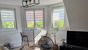 Een moderne woonkamer met een bank, stoelen, een televisie en een eettafel.