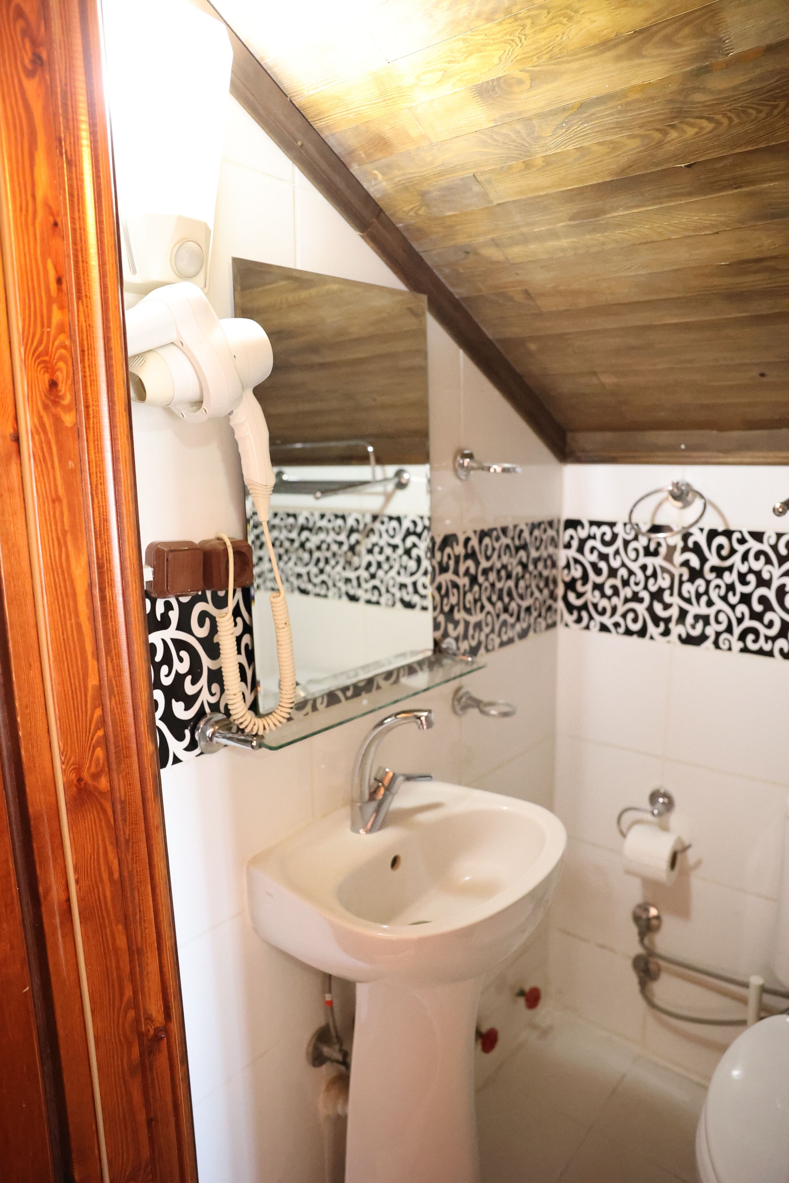 A bathroom with a white sink, a mirror, and a toilet.