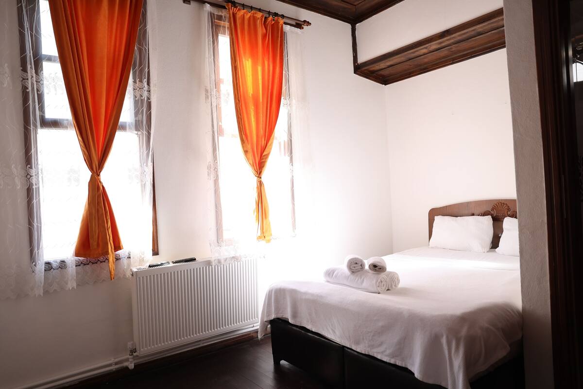 A bedroom with a bed, a radiator, and curtains.