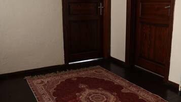 Un pasillo con dos puertas de madera y un tapete estampado en el suelo.