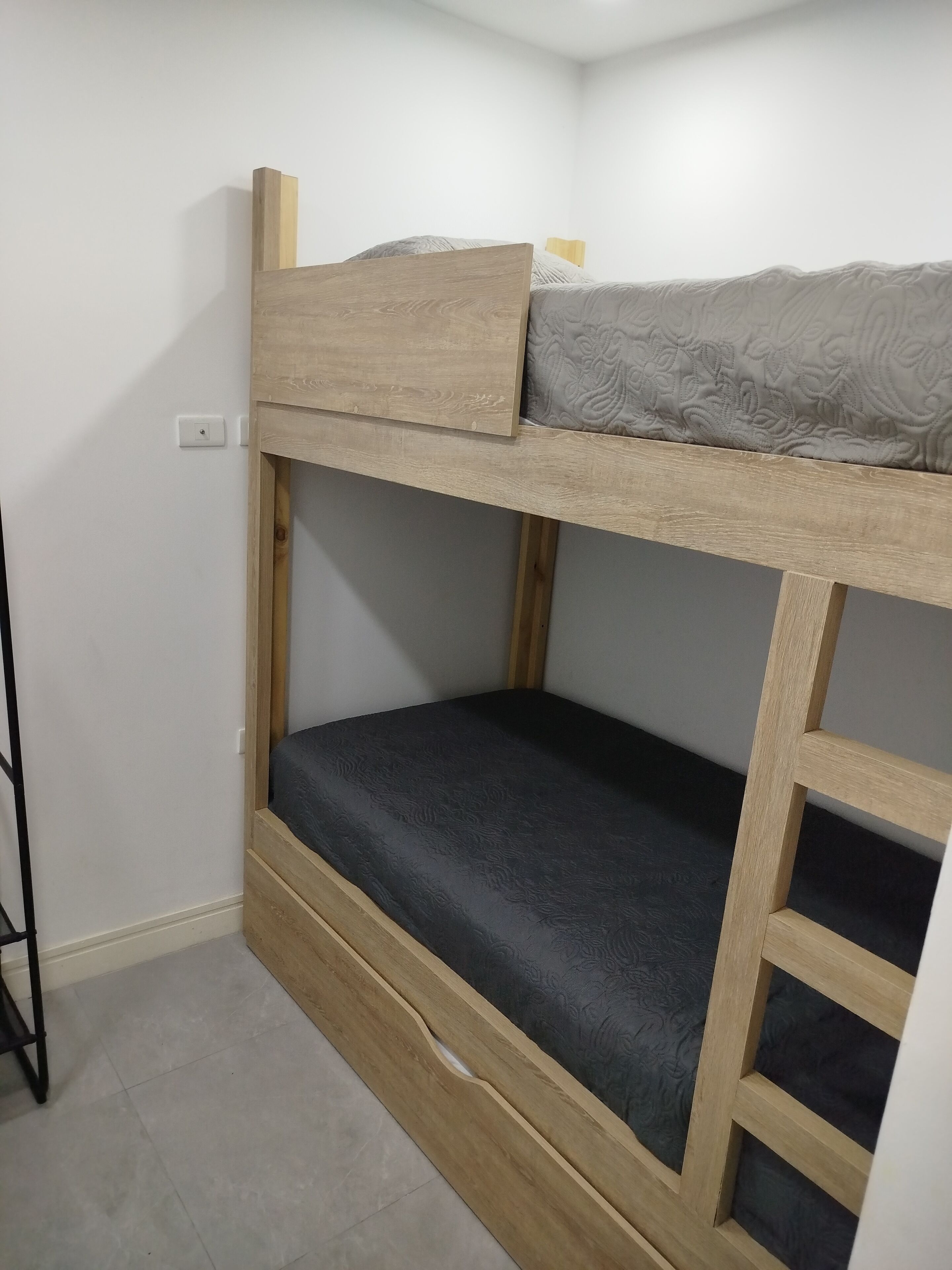 Una cama literera con estructura de madera y colchón gris.