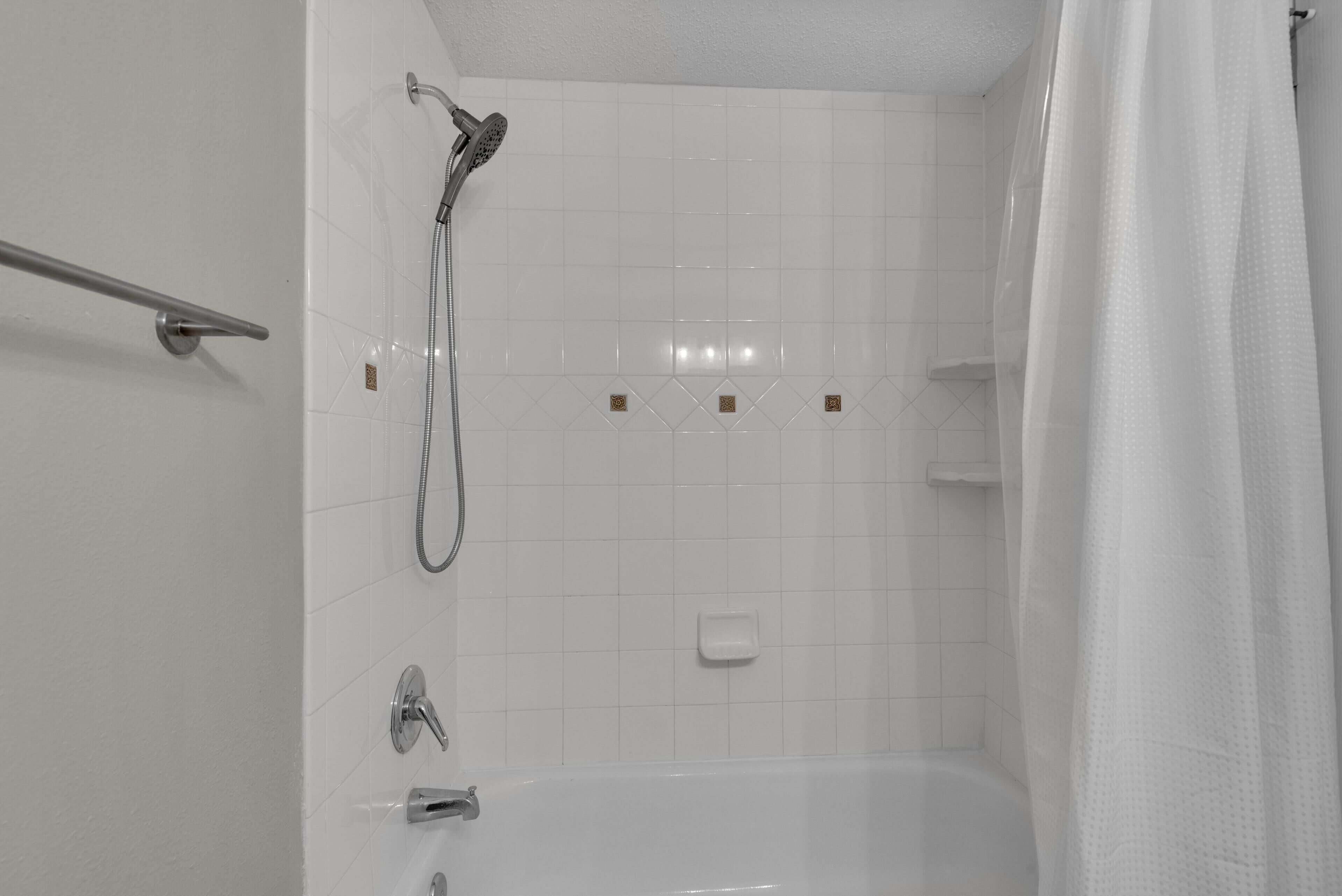Une salle de bain équipée d’une baignoire, d’une douche et d’une barre d’appui.