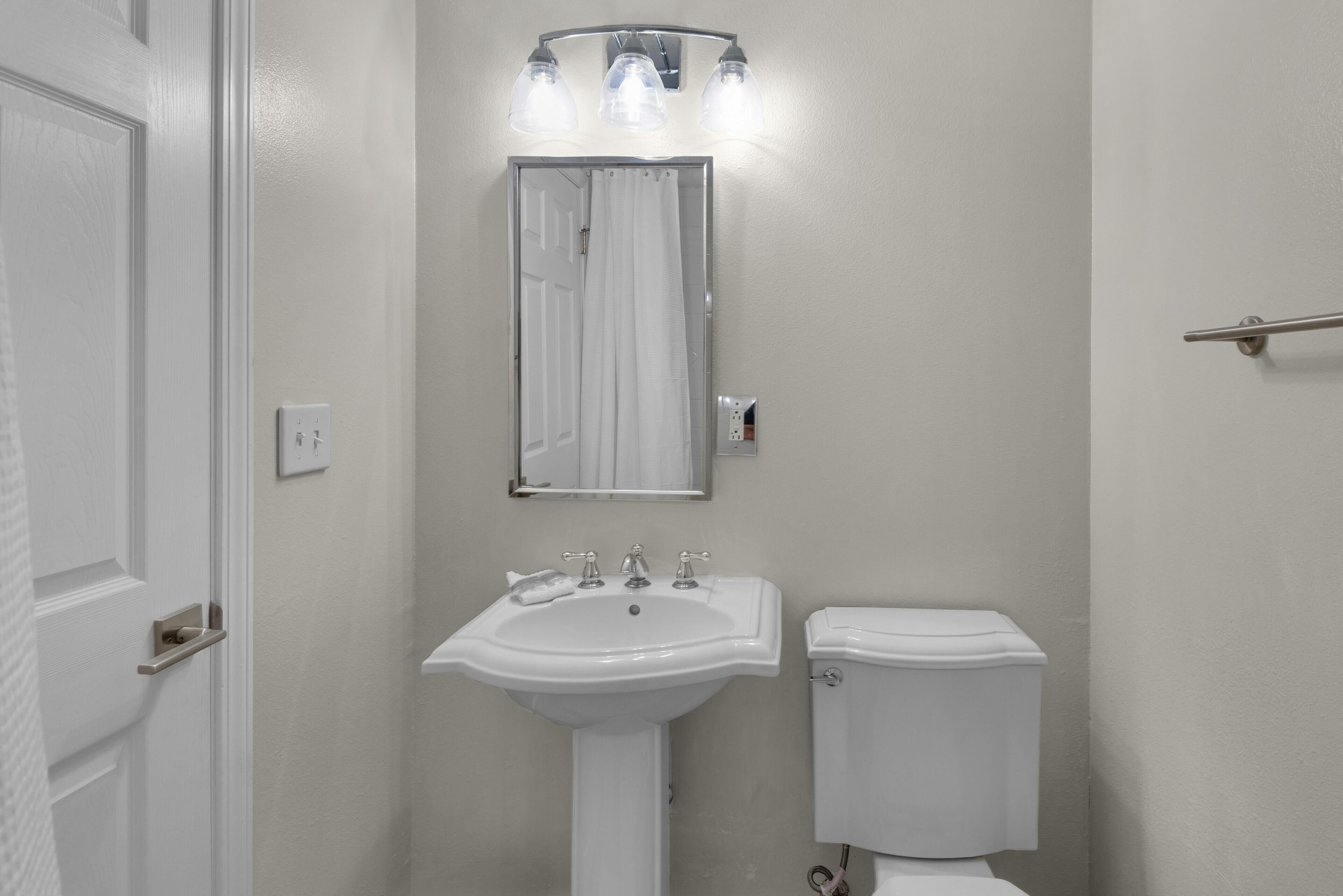 Een badkamer met een witte wastafel, een spiegel en een toilet.
