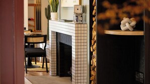 A room with a tiled fireplace, a cactus, and a wooden sculpture on a shelf. - Modal House: A Fun-Filled Designer Home Just Steps from Downtown Main Street (Greenville)
