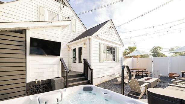 A backyard with a hot tub, outdoor furniture, and a staircase leading to a house. - Modal House: A Fun-Filled Designer Home Just Steps from Downtown Main Street (Greenville)